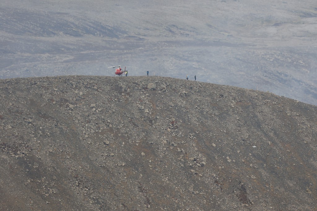 A helicopter and volcano tourists on another ridge