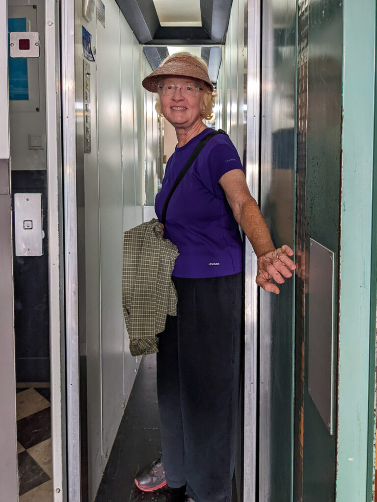 Pam stands in the very narrow elevator